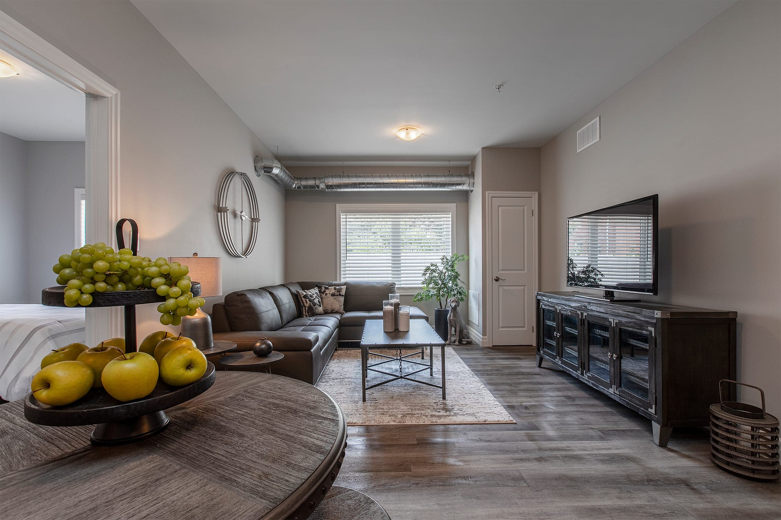 Living and dining room in a suite at The Frontenac, with a sectional and a spiral duct along the ceiling