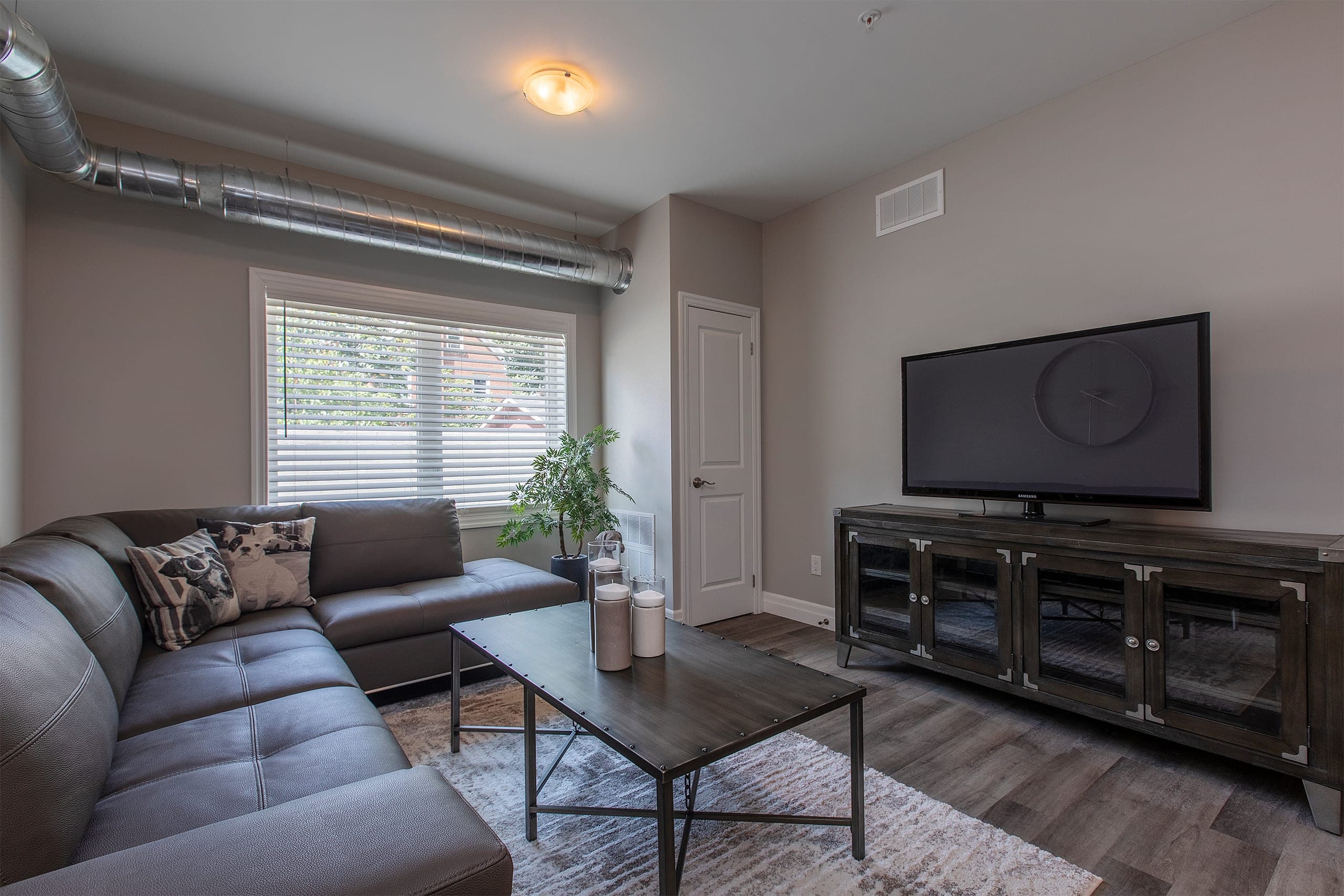Living room in a finished suite at The Frontenac, with a sectional and a spiral duct along the ceiling